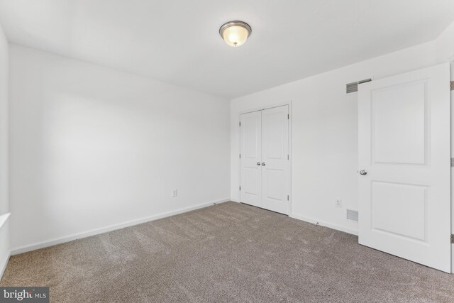 unfurnished bedroom with a closet, carpet flooring, visible vents, and baseboards