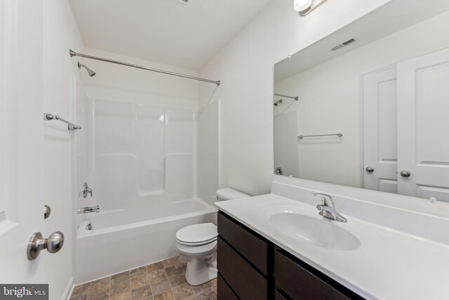 full bathroom featuring visible vents, toilet, stone finish floor, vanity, and washtub / shower combination