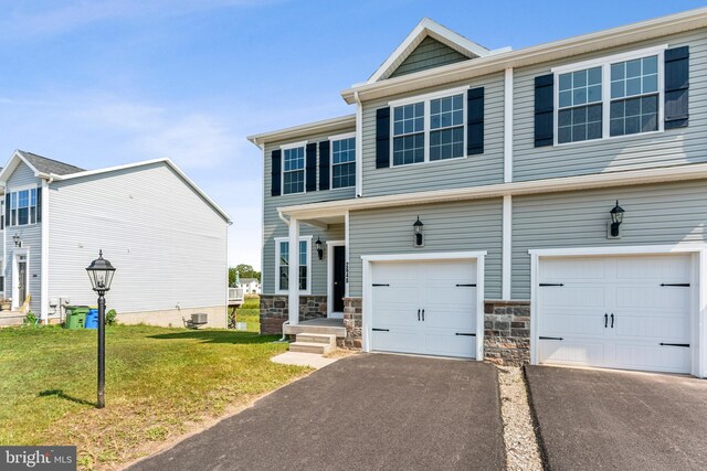 view of property featuring a garage, stone siding, aphalt driveway, cooling unit, and a front lawn