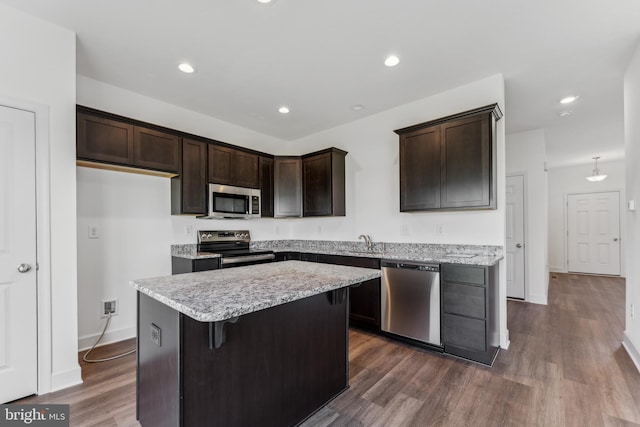 kitchen featuring a kitchen island, a sink, dark brown cabinets, appliances with stainless steel finishes, and dark wood-style floors