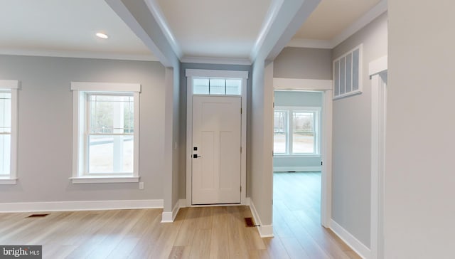 entrance foyer with ornamental molding and light hardwood / wood-style flooring