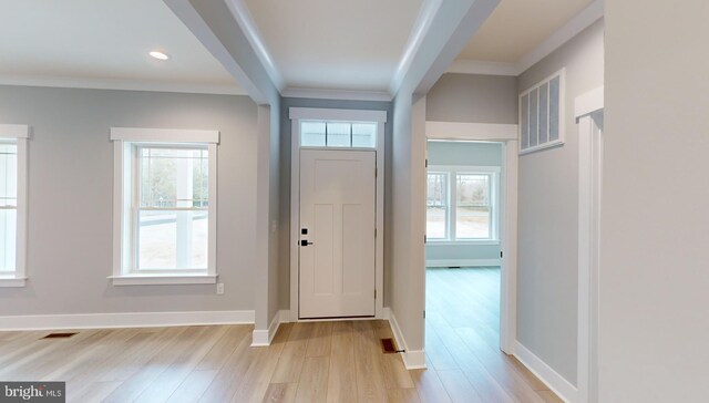 spare room featuring light wood-type flooring, ornamental molding, and a wealth of natural light