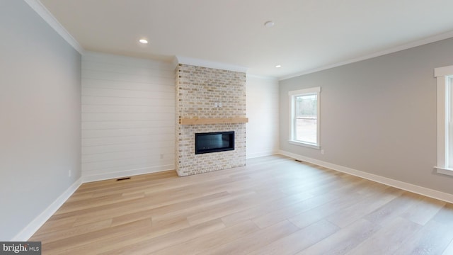 unfurnished living room featuring a fireplace, light wood-type flooring, and crown molding