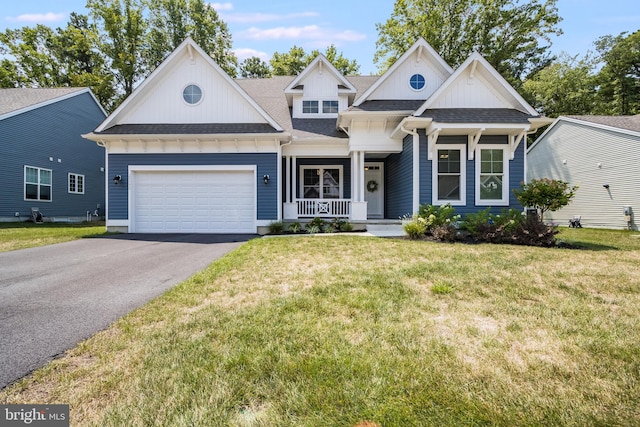 view of front of property featuring a garage, a front lawn, and covered porch