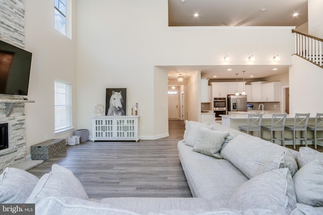 living room featuring a high ceiling, a fireplace, light wood-type flooring, and a wealth of natural light