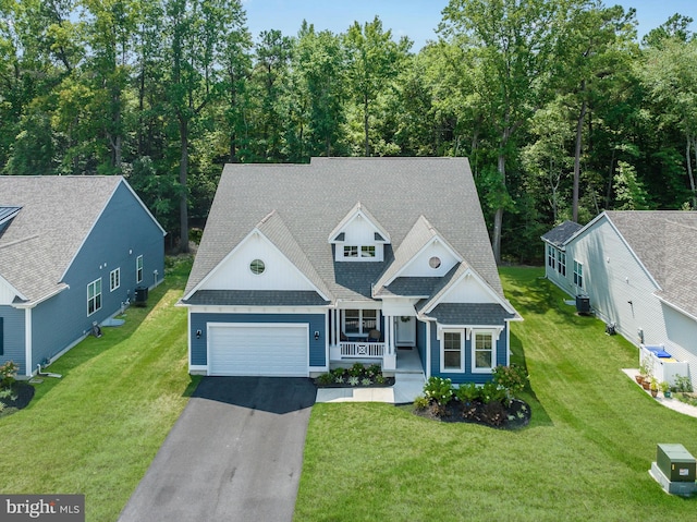 view of front of home featuring covered porch, a garage, cooling unit, and a front yard