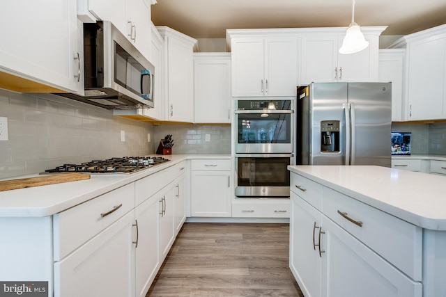 kitchen featuring white cabinetry, tasteful backsplash, light hardwood / wood-style floors, appliances with stainless steel finishes, and decorative light fixtures