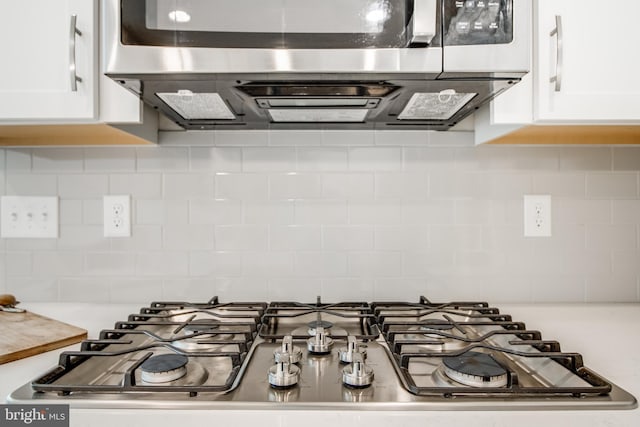 interior details with stainless steel gas cooktop, white cabinetry, and backsplash