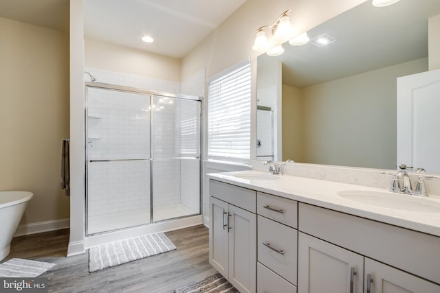 bathroom featuring wood-type flooring, a shower with shower door, toilet, and dual bowl vanity