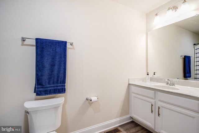 bathroom featuring vanity, wood-type flooring, and toilet