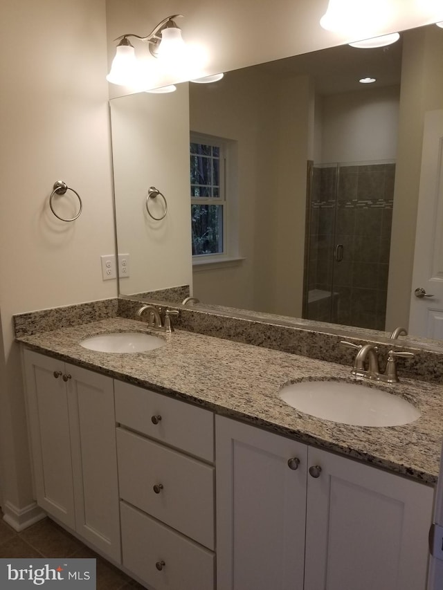 bathroom featuring dual vanity, a shower with door, and tile patterned flooring