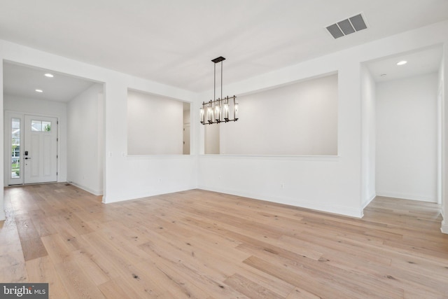 unfurnished dining area with baseboards, wood-type flooring, visible vents, and an inviting chandelier