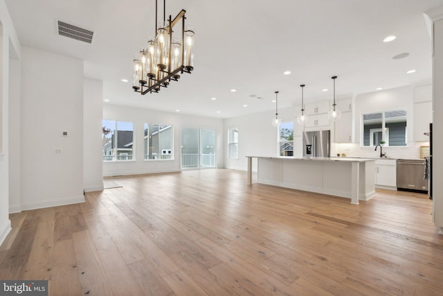 unfurnished living room with light wood finished floors, baseboards, visible vents, a sink, and recessed lighting