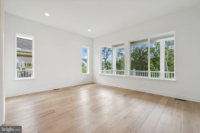 spare room featuring baseboards, visible vents, plenty of natural light, and light wood finished floors