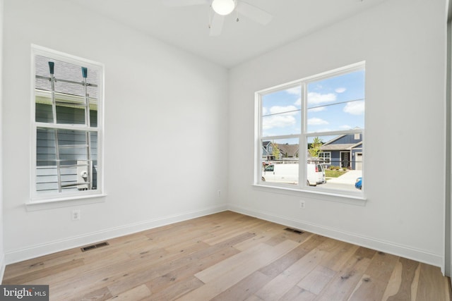 spare room with a ceiling fan, baseboards, visible vents, and hardwood / wood-style floors