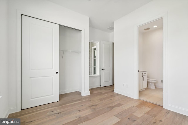 unfurnished bedroom with baseboards, visible vents, light wood-style flooring, ensuite bathroom, and a closet