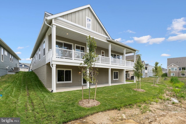 back of property with a patio area, a yard, board and batten siding, and brick siding