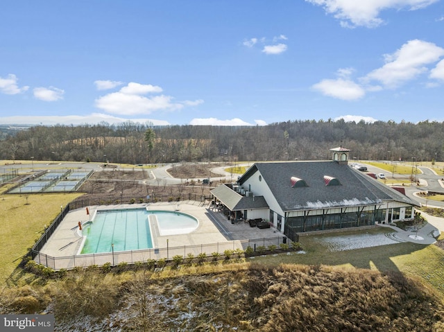 community pool featuring fence, a view of trees, and a patio