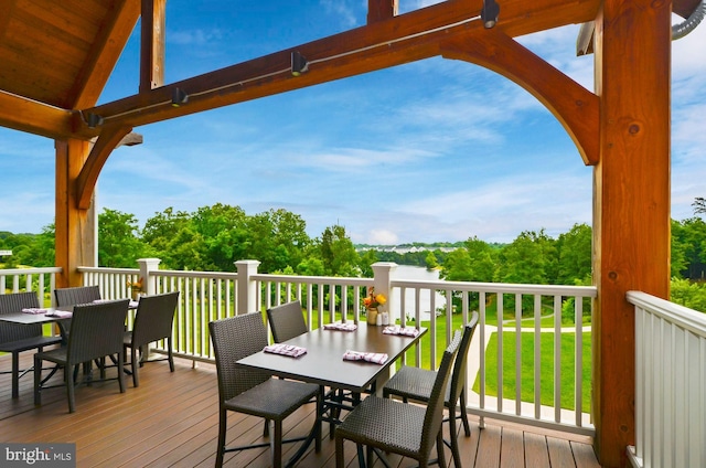 wooden terrace with outdoor dining area and a lawn