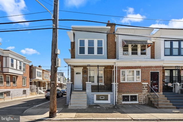 multi unit property with central AC, brick siding, a chimney, and a residential view