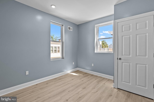 empty room featuring visible vents, light wood finished floors, and baseboards