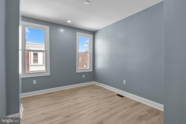 empty room featuring light wood-type flooring, visible vents, and baseboards