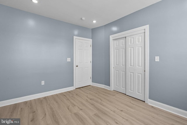 unfurnished bedroom with light wood-type flooring, baseboards, a closet, and recessed lighting