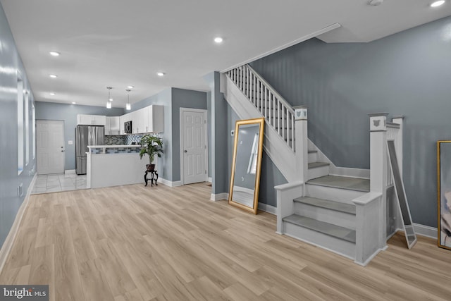 unfurnished living room featuring light wood-style flooring, stairs, baseboards, and recessed lighting