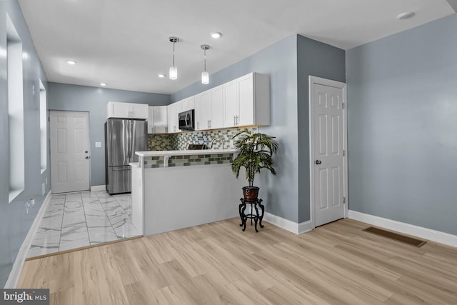 kitchen featuring stainless steel appliances, visible vents, decorative backsplash, white cabinets, and a peninsula