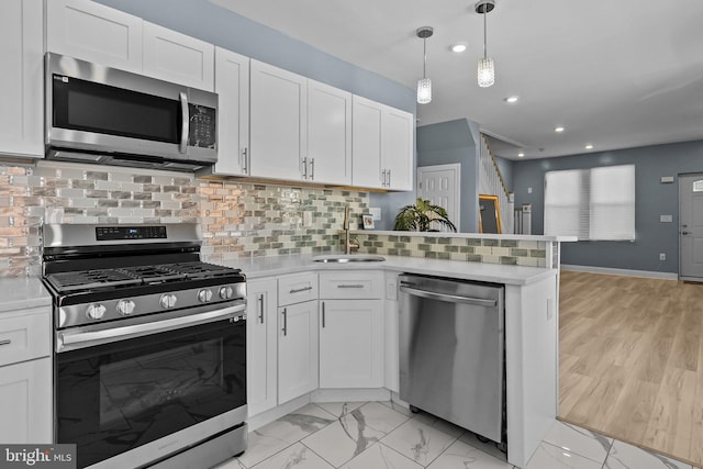 kitchen with stainless steel appliances, white cabinets, light countertops, and a sink