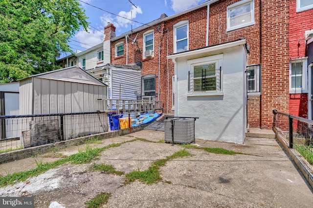 back of house featuring a storage unit