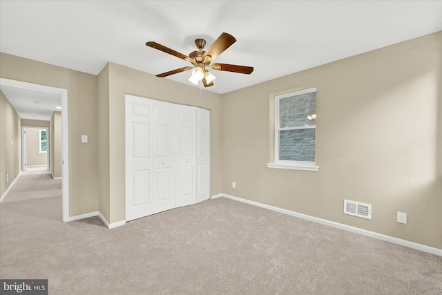 unfurnished bedroom featuring light colored carpet, ceiling fan, and a closet