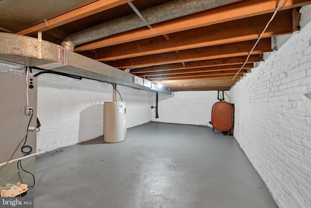 basement featuring electric water heater and brick wall