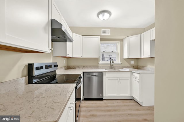 kitchen with appliances with stainless steel finishes, sink, wall chimney range hood, and white cabinets