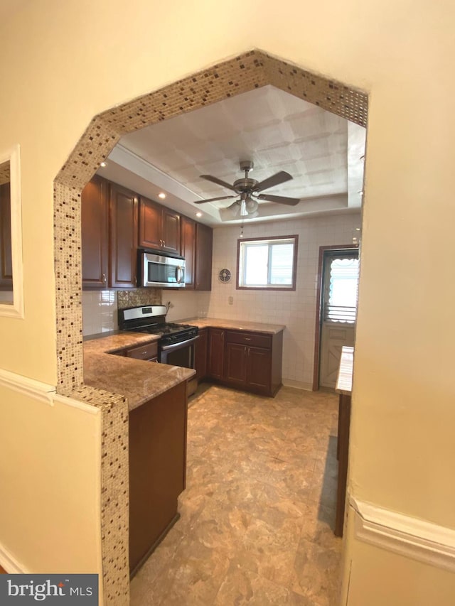 kitchen with light tile patterned flooring, ceiling fan, backsplash, and stainless steel appliances