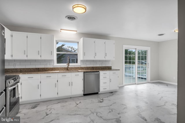 kitchen featuring sink, white cabinetry, dark stone countertops, stainless steel appliances, and tasteful backsplash