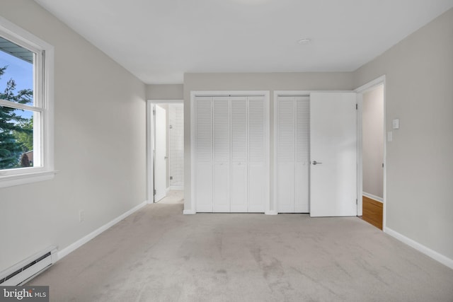 unfurnished bedroom with multiple closets, light colored carpet, and a baseboard radiator