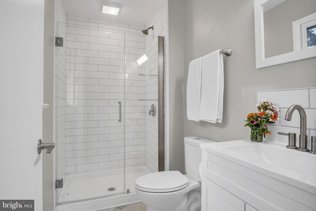 bathroom featuring a shower with shower door, vanity, and toilet