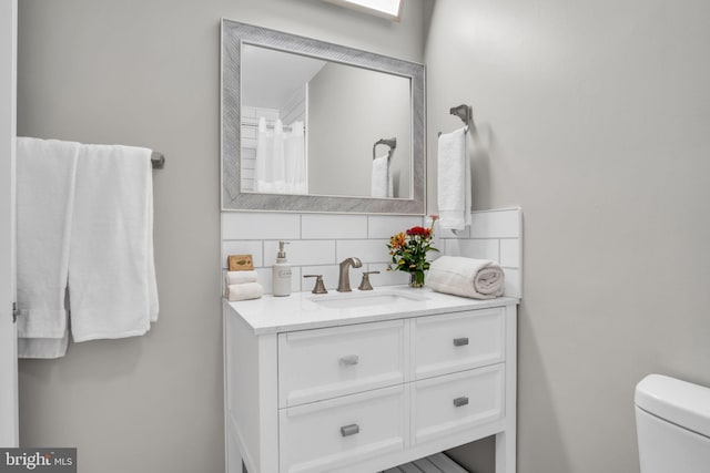 bathroom with vanity, toilet, and backsplash