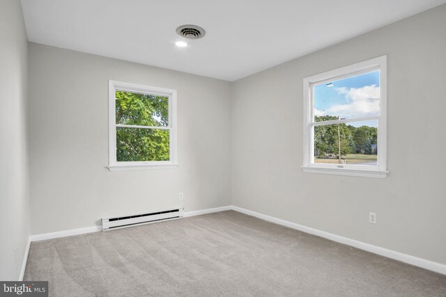 carpeted empty room with a baseboard heating unit and a wealth of natural light