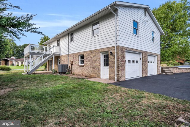 view of home's exterior featuring a garage, central AC, a wooden deck, and a yard