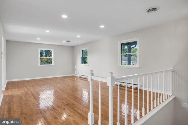 spare room featuring a baseboard heating unit and light hardwood / wood-style flooring