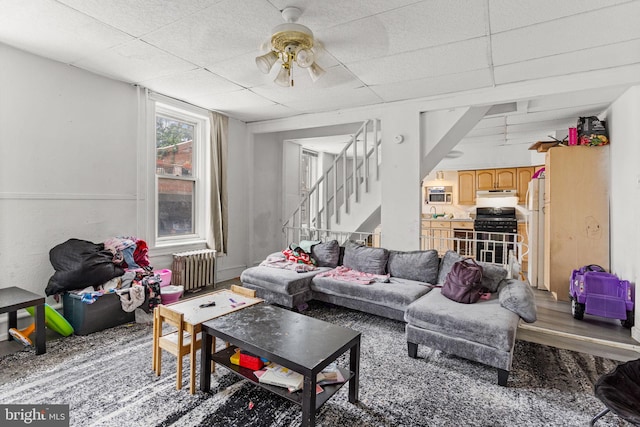 living room with radiator heating unit, a paneled ceiling, and ceiling fan