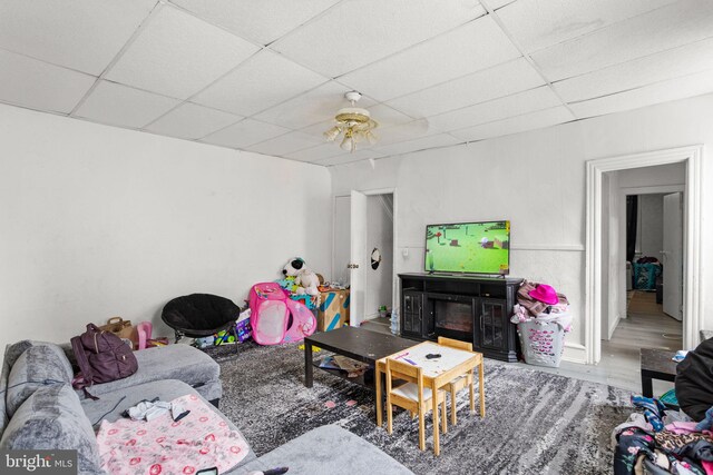 living room with ceiling fan, a drop ceiling, and hardwood / wood-style flooring