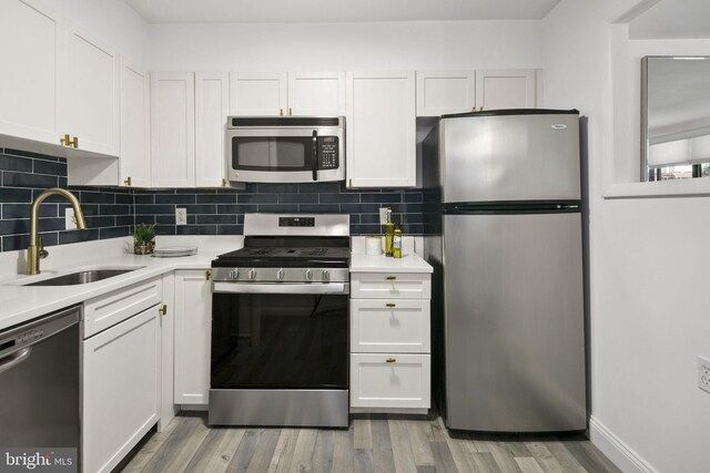 kitchen with light hardwood / wood-style floors, white cabinetry, sink, and stainless steel appliances