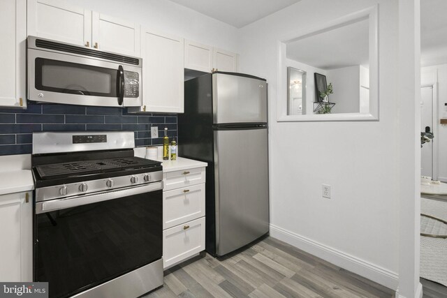 kitchen featuring white cabinets, stainless steel appliances, light hardwood / wood-style floors, and tasteful backsplash