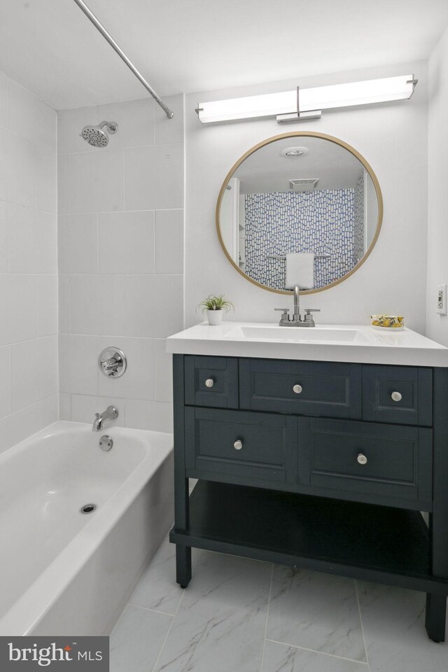 bathroom with tiled shower / bath combo and vanity