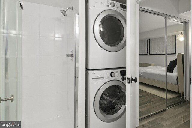 laundry area with hardwood / wood-style floors and stacked washing maching and dryer