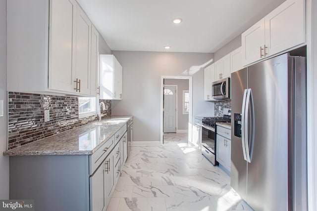 kitchen featuring white cabinets, stainless steel appliances, backsplash, and light tile patterned floors