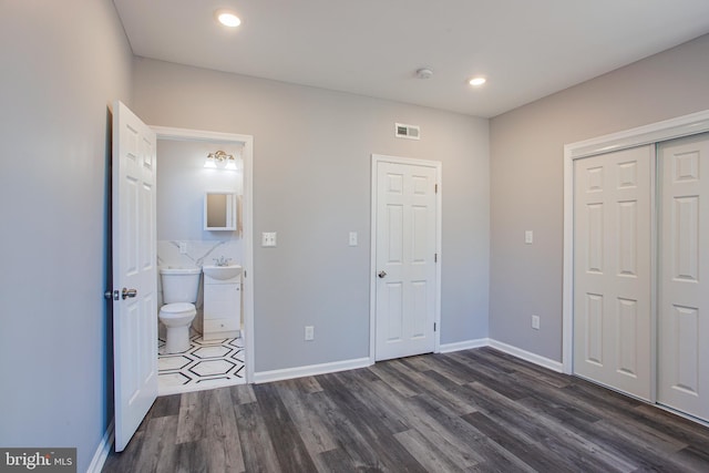 unfurnished bedroom featuring sink, a closet, tile walls, and dark wood-type flooring